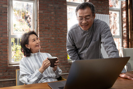 Happy elderly couple using laptops
