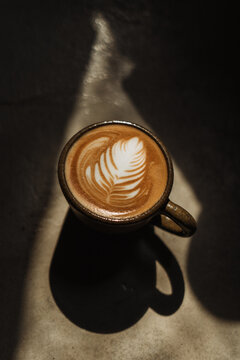 A cup of Coffee latte on the Cement floor in sunlight