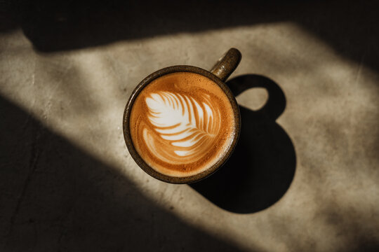 A cup of Coffee latte on the Cement floor in sunlight