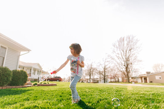Girl twirling around blowing bubbles. 