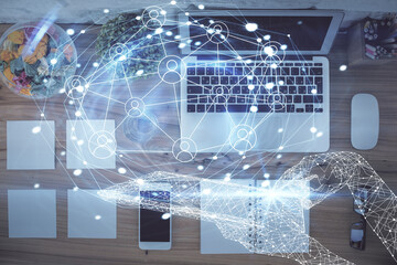 Social network hologram drawings over computer on the desktop background. Top view. Double exposure.