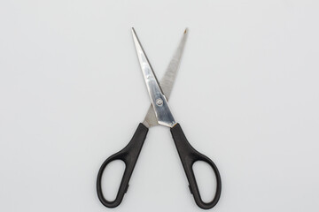 Forbici aperte con manico nero fotografate su sfondo bianco