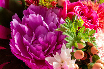 ピンク系統にまとめられた薔薇やカーネーションのフラワーアレンジメント