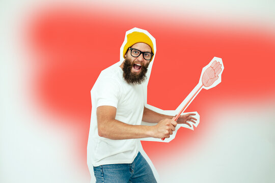 Young caucasian hipster man holding a fly swatter wanting to kill annoying mosquito or a fly.