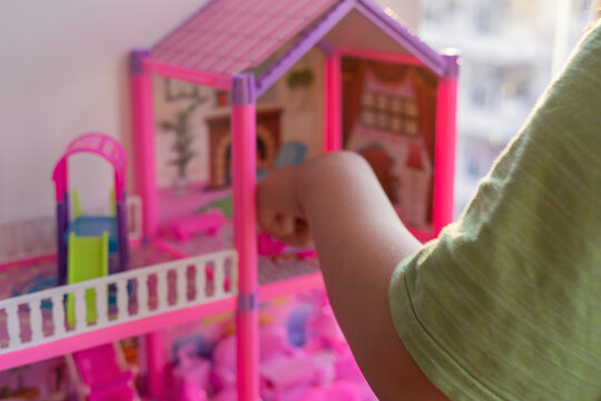 Blurry Photo Of A Child Playing With A Pink Doll House.