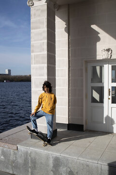 Beautiful  girl with a skateboard on a river station