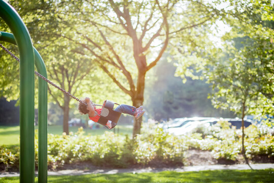 Girl swings high on park swing
