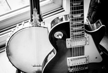 Ancient and Modern - modern single-cut electric guitar standing in front of an antique fretless banjo.