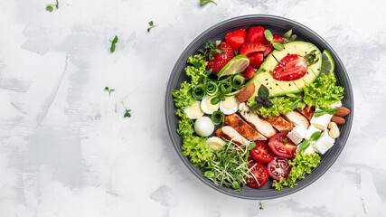 Healthy keto, ketogenic lunch menu with grilled chicken meat, avocado, feta cheese, quail eggs, strawberries, nuts and lettuce. Roasted chicken breast, fillet and fresh vegetable salad, top view