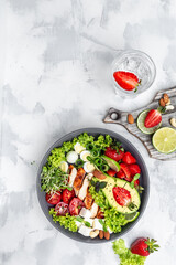 Healthy buddha bowl lunch with grilled chicken and avocado, feta cheese, quail eggs, strawberries, nuts and lettuce. Delicious balanced food concept. vertical image. top view. place for text