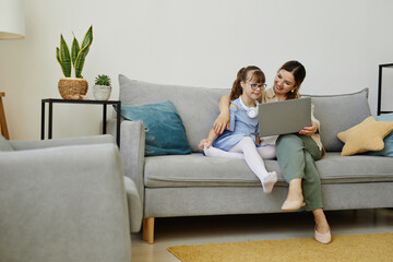 Portrait of young woman using laptop with cute girl with disability, copy space