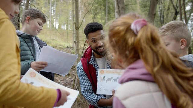 African-american teachers with group of small children outdoors in nature, learning group education concept.