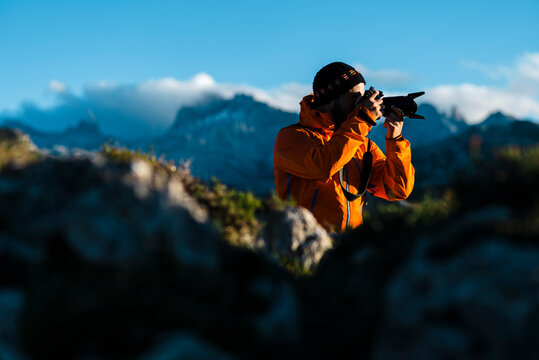 Adult hiker using digital SLR camera in craggy mountains