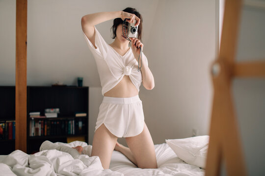 Woman holding film camera and taking selfie


