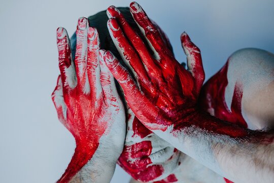 Man covering eyes with painted hands
