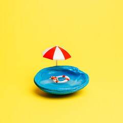 Blue shell as a metaphor for a pool with an umbrella and miniature man in inflatable swimming ring...