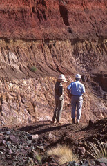 Two mine workers standing on the edge above an open cut gold mine pit