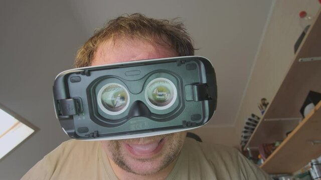 Portrait of funny male scientist in virtual reality glasses with crazy big eyes in home laboratory.