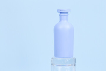 Unbranded blue shampoo or sunscreen cream bottle for branding and label on glass podium on blue background. Mockup, copy space. Isolated on blue. Front view of Cosmetic bottle, minimalism.