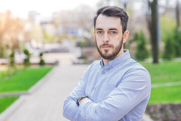 Portrait of a businessman with beard who crossed his arms on a sunny day