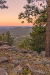 In Payson, Arizona this is known as the Mogollon Rim. The sun sets looking out over the rim, through the trees, the colorful sky paints the ledge and flowing hills, boulders and trees colorful shades 