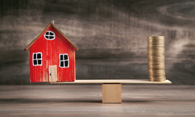 Coins and house on the wooden scales in balance.