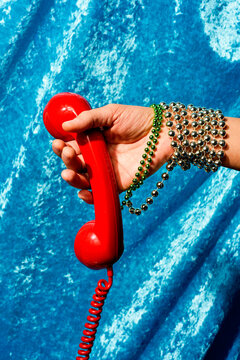 man holding the handset of a red telephone in his hand