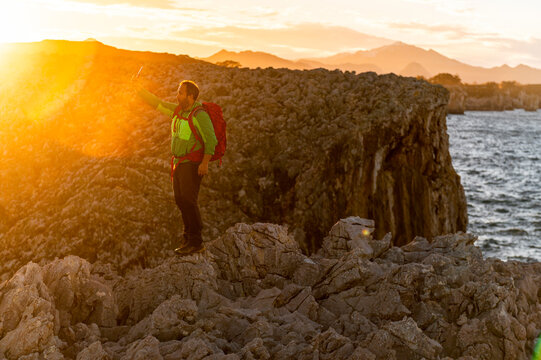 Backpacker taking selfie in seacliff at sunset 
