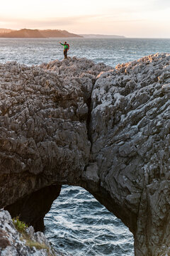 Traveller taking selfie with smartphone in seacliff at sunset 