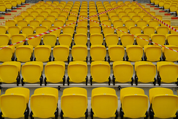 Fototapeta premium The seats in the football fields were blocked from sitting,Yellow chairs on the football field forbid people to sit.