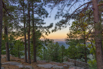 In Payson, Arizona this is known as the Mogollon Rim. The sun sets looking out over the rim, through the trees, the colorful sky paints the ledge and flowing hills, boulders and trees colorful shades 
