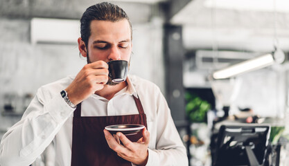 Portrait of barista man small business owner holding cup of coffee in the cafe or coffee shop.Male barista standing at cafe