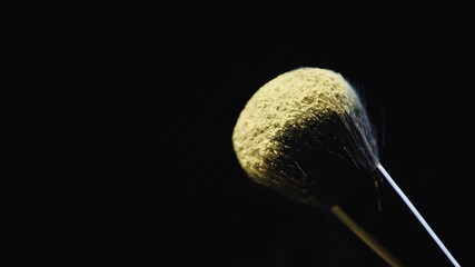 yellow holi paint on soft cosmetic brush isolated on black