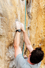 Hands with smart watch of person climbing a vertical rock. mountain sports and activities concept.