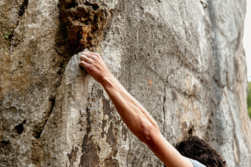 detail of hand clinging to the rock during a sport climbing session. climber overcoming an...