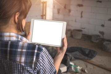 Girl with a tablet in front of an unfinished house, repair, construction concept, copy space photo
