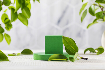 Green podium surrounded by young leaves, for product presentation on a wooden background. The...