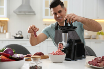 Man using modern meat grinder in kitchen