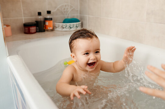 Happy toddler splashing water in bathtub