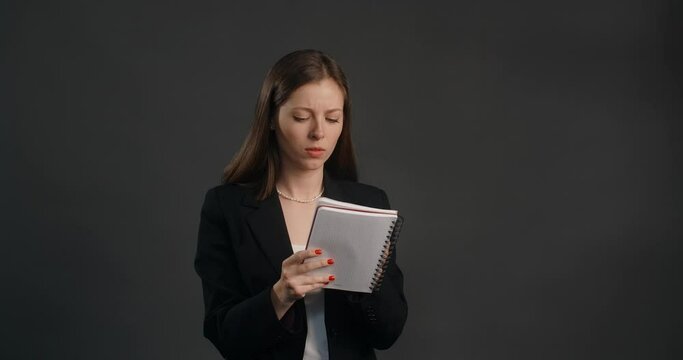 Vexed and angry woman in black suit crosses out hes notes in the notepad, crumples sheet of paper and throws it away, 4k Prores HQ