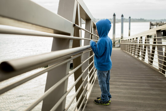 Boy peers out through metal dock railing
