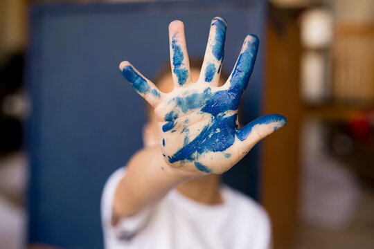 Child's hand covered in blue paint

