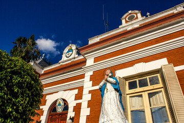 Facade of an old school with a Virgin Mariah statue in the city of Parana - Entre Rios, Argentina -...