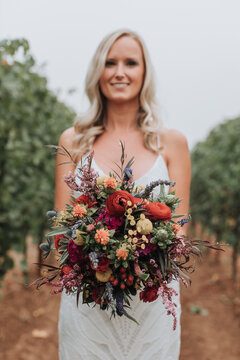 Portrait of Beautiful Bride Holding Bouquet in Vineyard