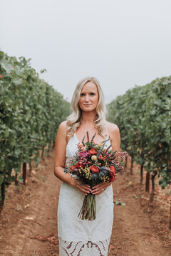 Portrait of Beautiful Bride Holding Bouquet in Vineyard
