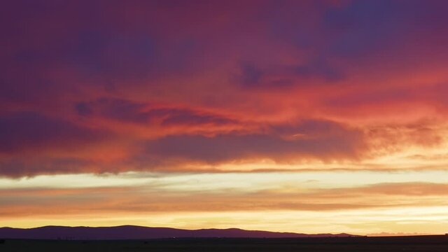 Timelapse of colorful clouds moving through the sky at sunset over the Wyoming landscape.