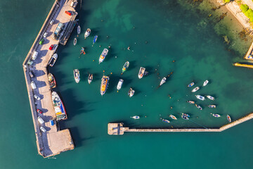 Top down view of boats in a marina and its pier with turquoise water