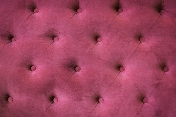 fabric upholstery on the back of a vintage sofa. Burgundy red background color