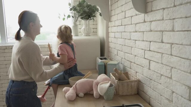 woman taking amputee child from kitchen counter