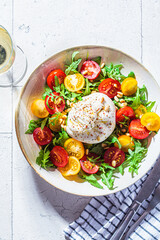 Burrata cheese salad with arugula, nuts and tomatoes.